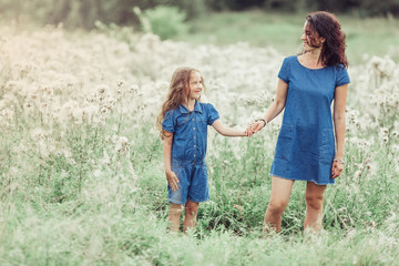 Happy mother and daughter outdoors in the summer having fun together. Motherhood, love, family, happiness concept