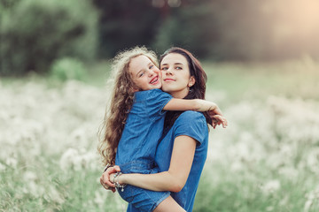 Happy mother and daughter outdoors in the summer having fun together. Motherhood, love, family, happiness concept