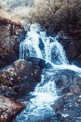 Waterfall in mountains. Rapid flow in river. Water in rocks, trip along river.