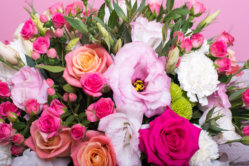 beautiful floral arrangement in the box, pink and yellow rose, pink eustoma, green and pink chrysanthemum, white carnation, pink dahlia on pink background with space for text.