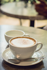 Hot coffee and hot tea place on the marble table in early morning with copyspace, white cup and silver spoon.