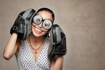 Lustige verrückte junge Frau mit großen Augen, Brillen und Boxhandschuhe
