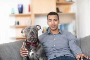 Junger Mann mit Hund zu Hause auf einem Sofa sitzend