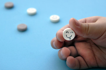 Close-up view of baby's hand holding a white tablet with a smiley face on a blue background