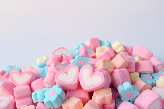 Pair of Pink and White Heart Shaped Marshmallow on the Pile of Pastel Color Flower Shaped Marshmallow Candies with Free Space for Text and Design 