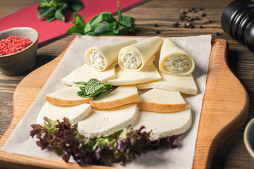Fototapeta na wymiar Slicing various cheeses on a wooden board