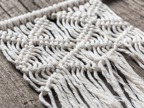 Macrame. Macrame weaving. White thread, wooden background, closeup