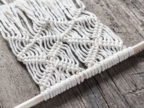Macrame. Macrame weaving. White thread, wooden background, closeup
