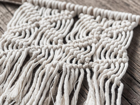 Macrame. Macrame weaving. White thread, wooden background, closeup