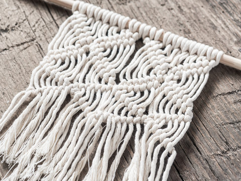Macrame. Macrame weaving. White thread, wooden background, closeup