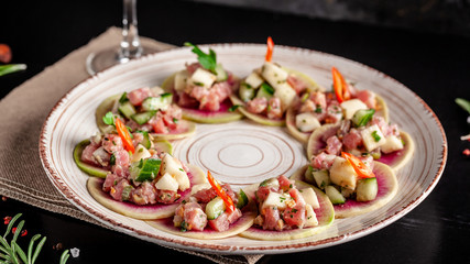 Concept of Spanish cuisine. Appetizer Tapas. Fresh tuna tartar, mussels, cucumber, apple, lemon, bitter, green onions, olive oil. Serving dishes in a restaurant on a ceramic plate. background image.