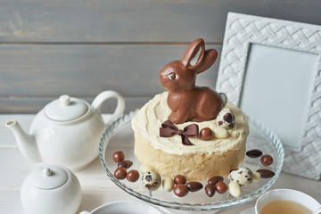 Rustic Easter Cake with Chocolate bunnies and Eggs. Easter greeting card background, closeup with copy space. Easter sweets for children. Chocolate bunny on decorated cake stand for Easter brunch.