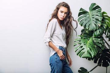 Young beautiful girl model Asian brunette with long hair posing in Studio with tropical plant on isolated background