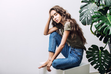 Young beautiful girl model Asian brunette with long hair posing in Studio with tropical plant on isolated background