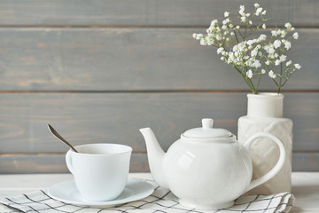 Fototapeta na wymiar Beautiful bright tea set up. White ceramic tea pots and tea ingredients, on top of the white table. Copy Space. Spring Greeting Card Template. Cup of tea on table. Kitchen utensils