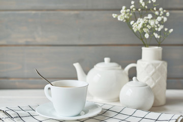 Fototapeta na wymiar Beautiful bright tea set up. White ceramic tea pots and tea ingredients, on top of the white table. Copy Space. Spring Greeting Card Template. Cup of tea on table. Kitchen utensils