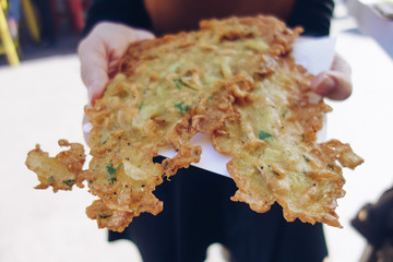 Woman holding Tortillita de camarón (shrimp tortillita) in hands. Typical tapa of Cadiz, Andalusia, Spain © Lia Aramburu