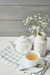Beautiful bright tea set up. White ceramic tea pots and tea ingredients, on top of the white table. Copy Space. Spring Greeting Card Template. Cup of tea on table. Kitchen utensils