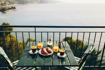 Delicious breakfast with coffee, pastry, and orange juice served on the balcony with sea view.