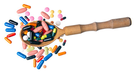 Colorful pills medical wooden spoon on white background top view, pharmacy concept