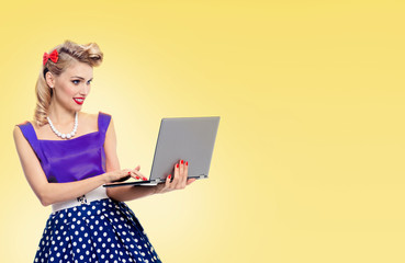 woman holding laptop, dressed in pinup style