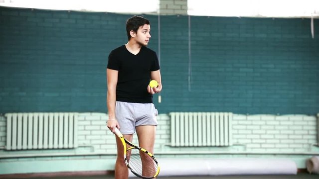 Training on the tennis court. Young man looking at the ball and then hitting it with a racket