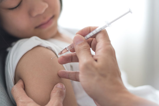 World immunization week and International HPV awareness day concept.Strong happy healthy Asia kid girl get vaccination influenza, flu shot, HPV prevention with doctor pediatrician hold medical syringe - Powered by Adobe