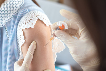 World immunization week and International HPV awareness day concept. Woman having vaccination for influenza or flu shot or HPV prevention with syringe by nurse or medical officer.