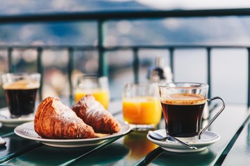 Delicious breakfast with coffee, pastry, and orange juice served on the balcony with sea view.