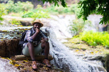 African Man Traveler with backpack smiling and relaxing freedom with waterfall