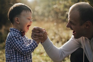 Fototapeta premium Handsome young father son competing in arm wrestling with cheerfull young son with bow tie.