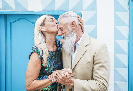 Happy senior couple having tender moments outdoor - Mature elegant people celebrating date of their anniversary - Wife kissing her husband -  Concept of love and relationship elderly lifestyle