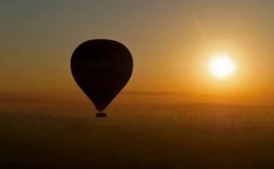 Luxor, Egypt. Balloon silhouette flying over the Nile at sunrise, seen from another balloon