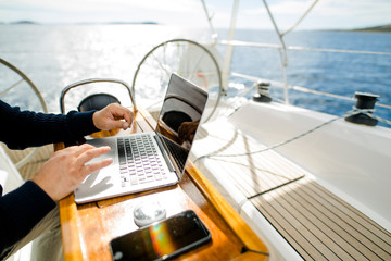 Digitaler Nomade mit Laptop arbeitet auf einem Segelboot - obrazy, fototapety, plakaty