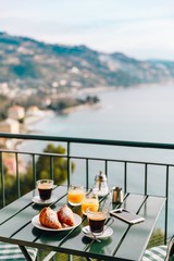 Delicious breakfast with coffee, pastry, and orange juice served on the balcony with sea view.