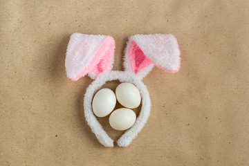 Top view of bunny ears easter holiday accessory and white egg on rustic background