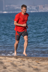Fototapeta na wymiar Young runner running in red t-shirt at springtime on the Spanish beach