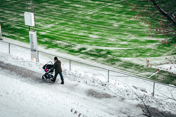 Walking with a stroller next to the football field. During winter.