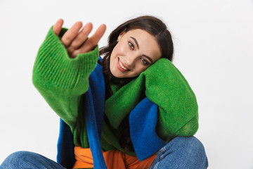Image of gorgeous woman 30s in colorful clothes propping her head while sitting on the floor,...