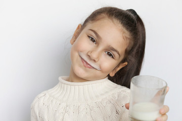 Happy cute child girl drinking yogurt on white background. Whiskers from yogurt