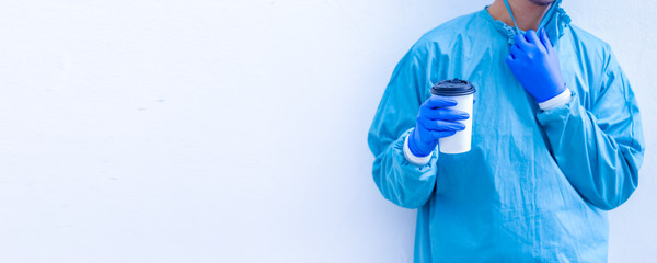 Doctor in blue scrubs relaxing with coffee break.Doctor or medic holding coffee to go cup isolated on white background.
