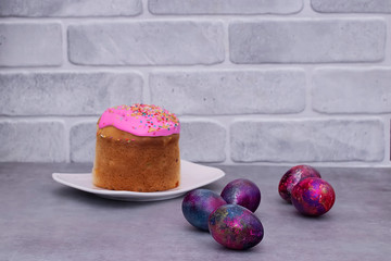 Traditional Easter cake and decorative multi-colored eggs on a gray background. Easter concept.