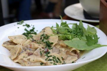 Traditional Slovenian meal called 'Idrijski zlikrofi' - dumplings made from dough with potato filling, served with bacon and mushroom sauce. Selective focus. 
