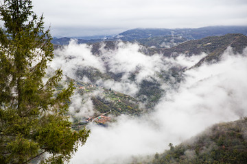 Panoramic top view of Alps mountains in fog and clouds, valley with clouds. Medieval buildings of Perinaldo town, Liguria, Italy