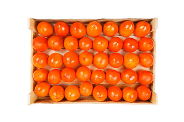 Juicy ripe persimmon in a large wooden box on a white background.