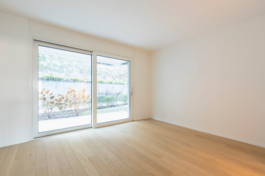 Empty room with parquet and window with garden view