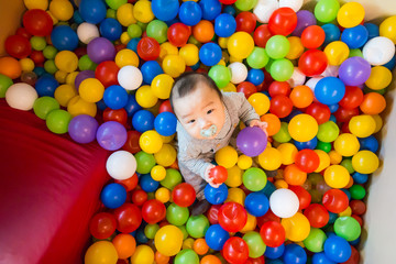 Fototapeta na wymiar Asian baby playing in colorful ball pool
