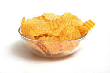 Bowl of tasty ridged potato chips on white background