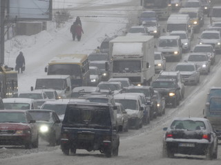Stream of cars on the snow track. Traffic jam on the snowy road. Car moving on a snowy road in the city.