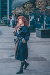 Confident attractive modern elegant woman in a long coat with thick long hair in the wind